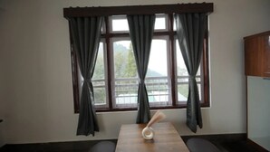 Ein Zimmer mit einem großen Fenster, einem Holztisch und einer Bank.