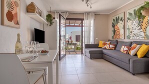 Ein modernes Wohnzimmer mit grauem Sofa, weißem Esstisch und Bildern an den Wänden.