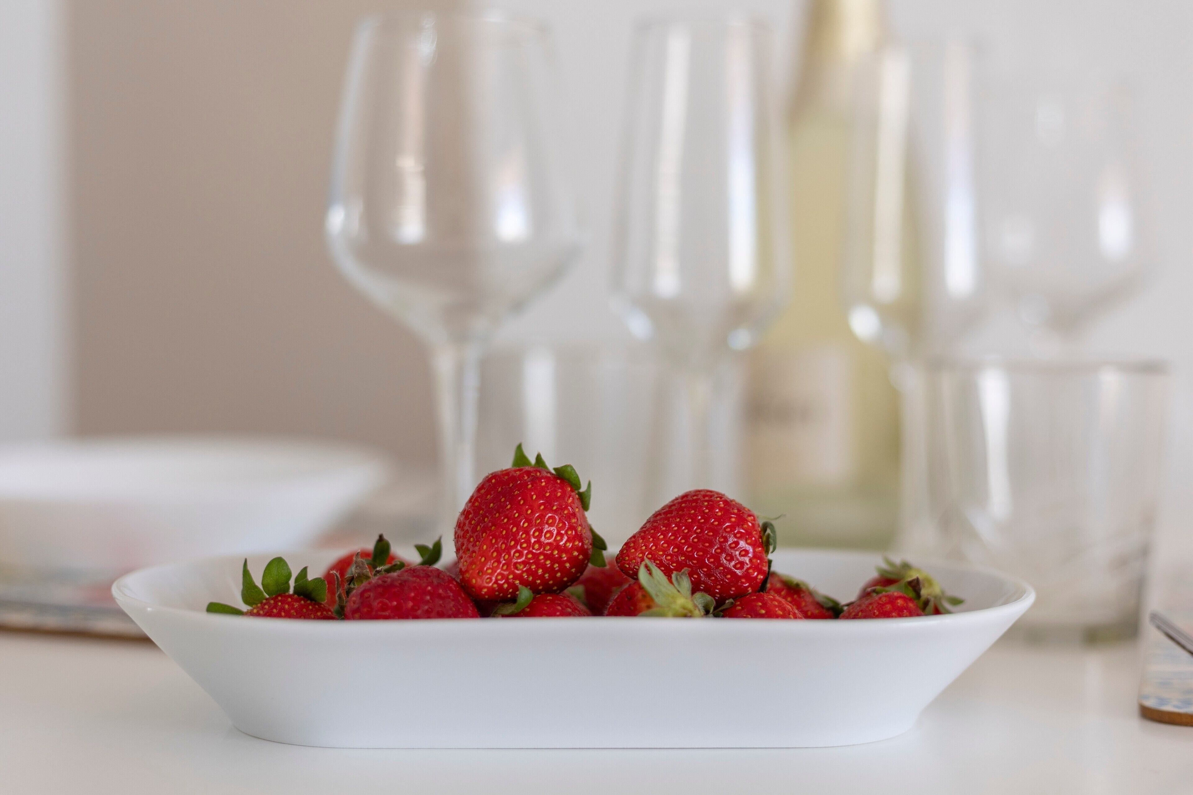 Un bol blanc rempli de fraises, posé sur une table.