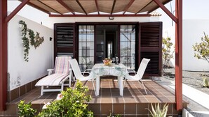 Eine überdachte Terrasse mit Tisch und Stühlen, einer hängenden Pflanze und Blick ins Haus.