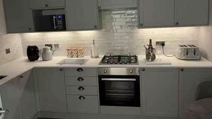 A modern kitchen with grey cabinets, a microwave, a gas stove, and a built-in oven. - Riverside House, Lancaster (Lancaster)
