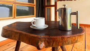 A wooden table with a white cup and a metal coffee pot. - Kibale Riverside Camp (Kibale)
