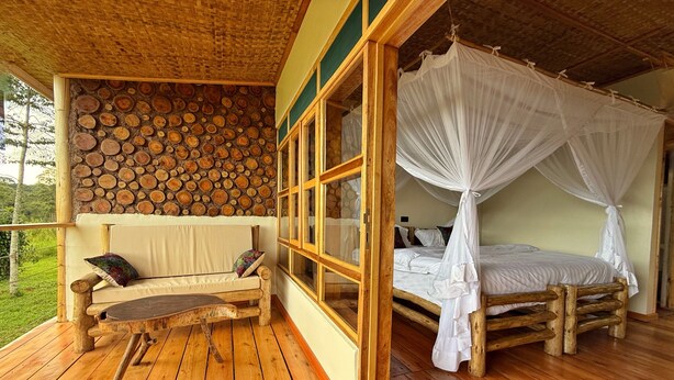 A wooden deck with a bench and a bed with a canopy. - Kibale Riverside Camp (Kibale)