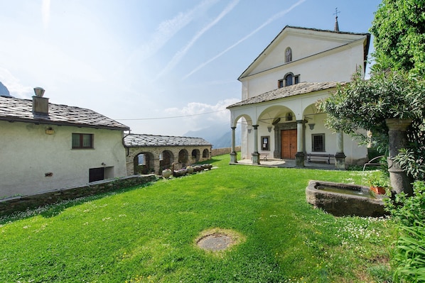 A courtyard with a fountain, a white building with arches, and a stone wall.