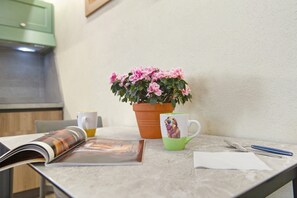 Una mesa con una revista, una taza con un perro, una planta en maceta y una cuchara.