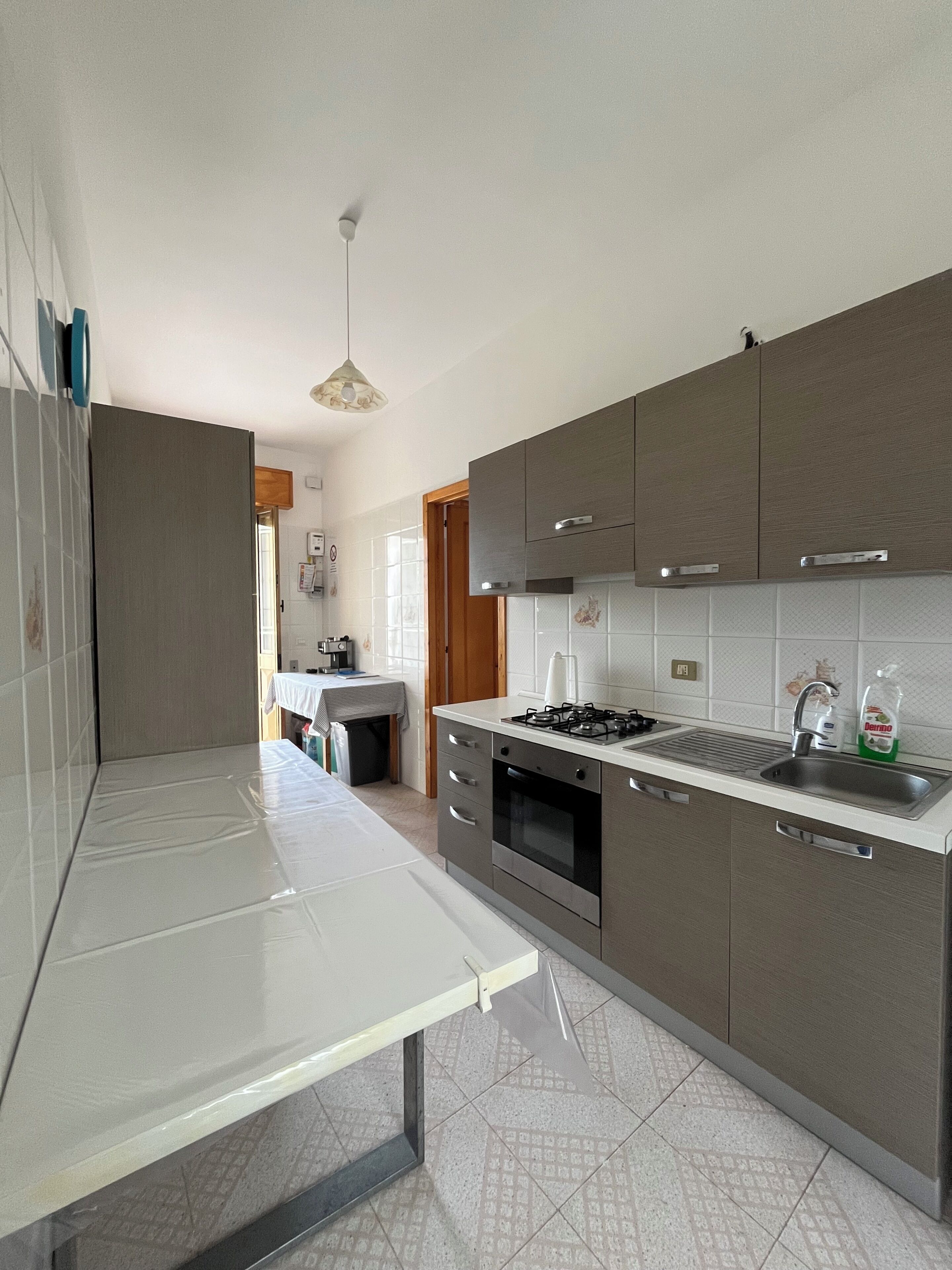 A modern kitchen with a gas stove, oven, and a sink. There is a dining area visible in the background.
