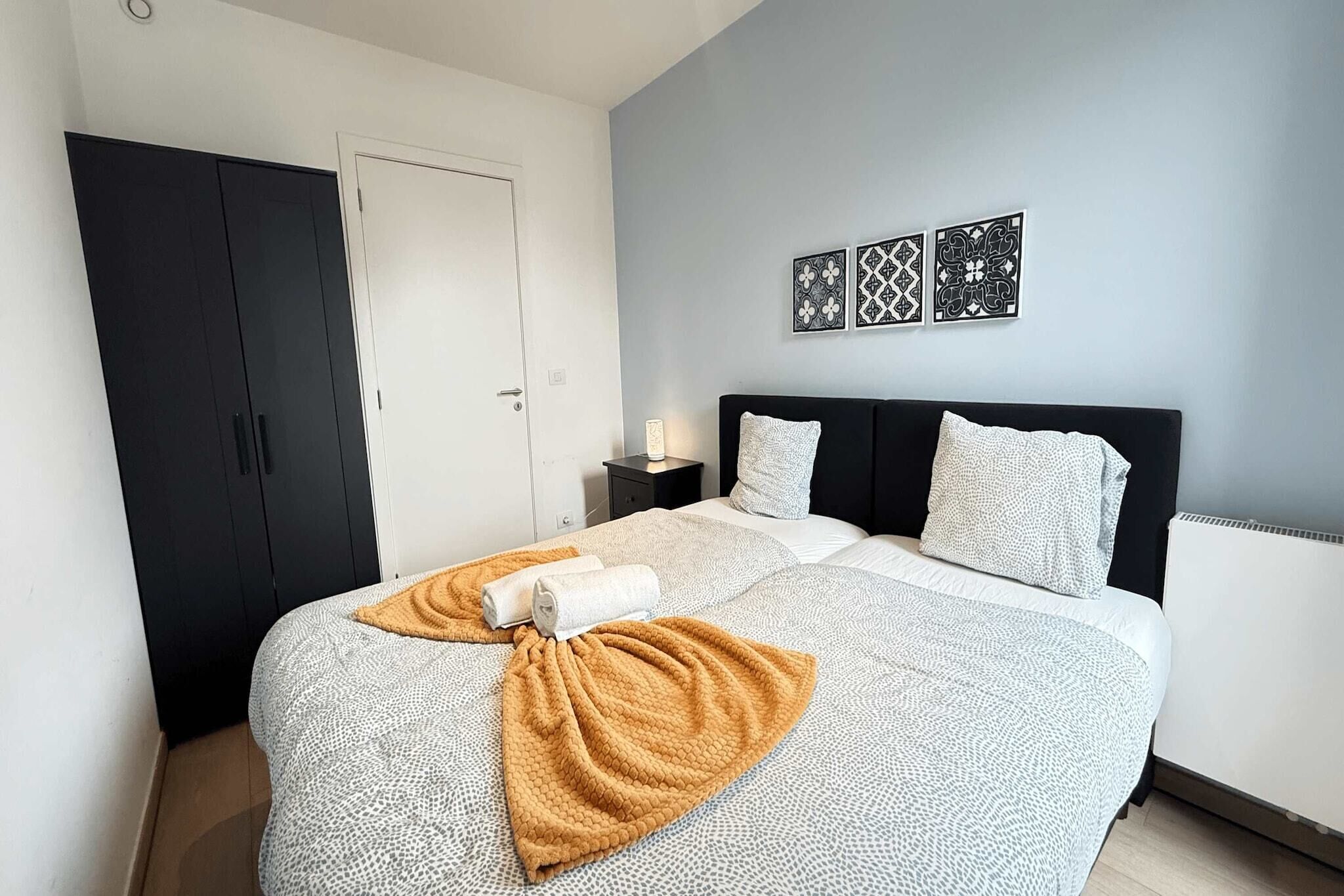 Et soveværelse med seng, garderobe, natbord og dekorative billeder på væggen.