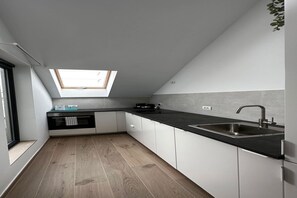 A modern kitchen with a skylight, a black countertop, and white cabinets. - Pleasant apartment in Antwerpen (Antwerpen)