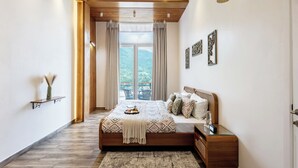 A bedroom with a bed, bedside table, nightstand, and a view of the outdoors. - ELIVAAS Antarmann Casa Mirage 3BHK Villa (Bhimtal)