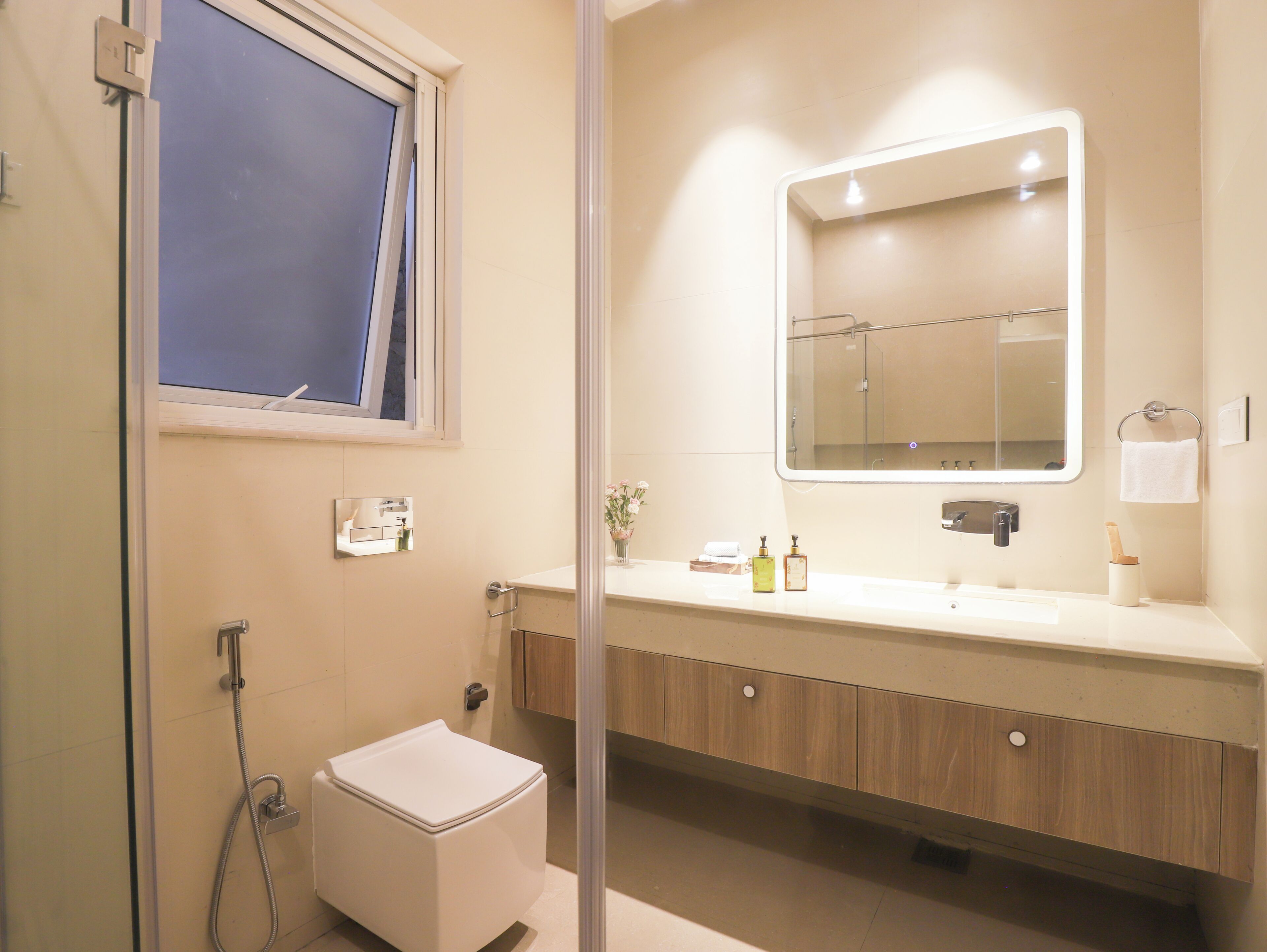 Un baño moderno con ducha, inodoro, tocador y un espejo grande.