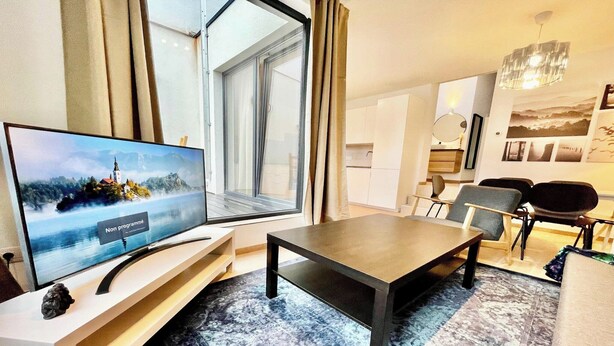 Un salon moderne avec un téléviseur, une table à manger et des chaises.
