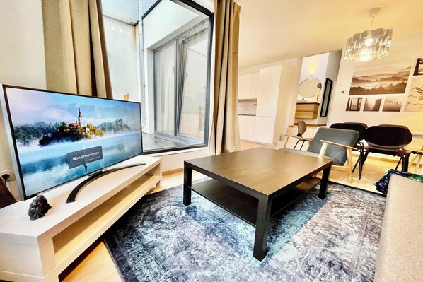 Ein modernes Wohnzimmer mit Fernseher, Esstisch und Stühlen.