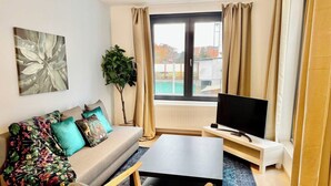 Un salon avec un canapé, une télévision et une plante.