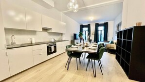 A modern kitchen with white cabinets, a dining table set for four, and a black shelving unit. - Antwerp Retreat with Kosher Kitchen (Antwerpen)