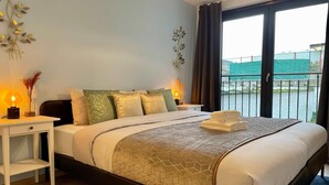 A hotel room with a bed, bedside tables, a view of a body of water, and a balcony. - Antwerp Retreat with Kosher Kitchen (Antwerpen)