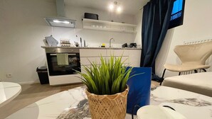 Cozinha moderna com forno embutido, pia e bancada. Há uma planta em vaso no primeiro plano.