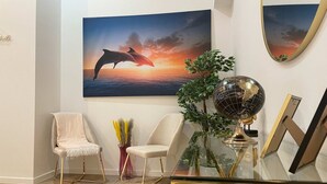 Een kamer met een glazen tafel, twee stoelen, een wereldbol en een ingelijste foto.