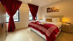 Ein Hotelzimmer mit Bett, Vorhängen, einem Gemälde und einem Nachttisch.
