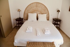 A neatly made bed with white linens, two bedside tables with lamps, and a woven headboard. - Luxury duplex overlooking the Etang de Thau (Sète)
