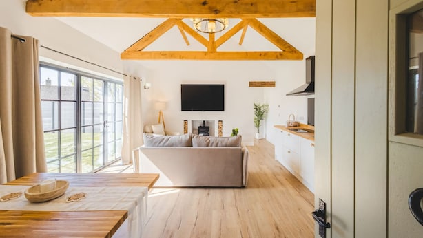 A modern interior with a wooden ceiling, a sofa, a TV, and a kitchen area. - The Annexe of Richmond Barn - Gateway to Cotswolds (Swindon)