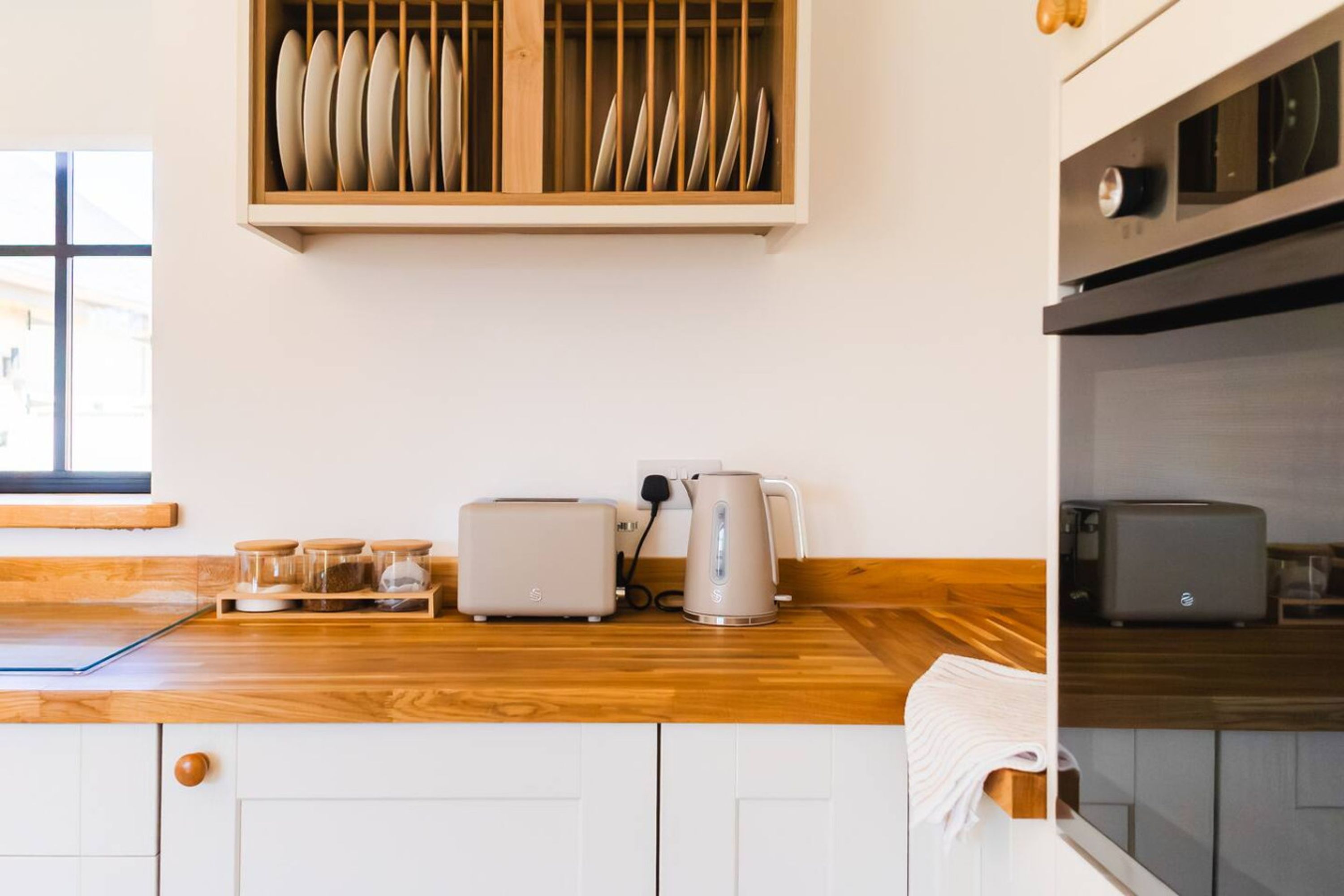A kitchen with wooden countertops, a toaster, a kettle, and a dish rack.