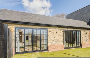 A building with large glass doors, stone walls, and a sloped roof. - The Annexe of Richmond Barn - Gateway to Cotswolds (Swindon)