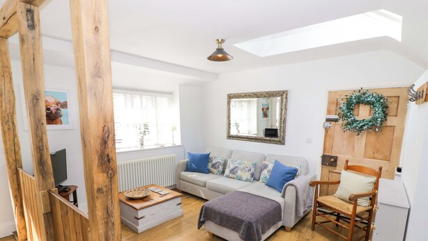 Una sala de estar acogedora con un sofá, una silla de madera, una mesita y un espejo en la pared.