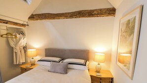 Un dormitorio con una cama, dos mesitas de noche, un radiador, un perchero y un cuadro en la pared.