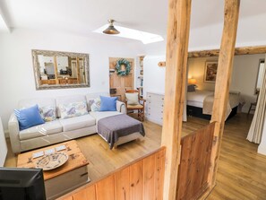 Una habitación acogedora con un banco de madera, un sofá con cojines estampados, un espejo y una cama con cabecera.