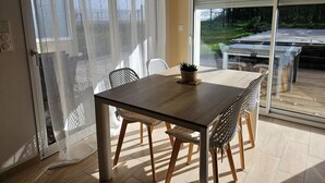 Ein Essbereich mit Tisch und Stühlen, einer Schiebetür aus Glas und Blick ins Freie.