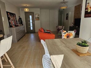 A modern living room with a wooden dining table, a sofa, and a chair. - Country house with swimming pool 7 minutes from the beach (SEMUSSAC)