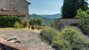 Un edificio in pietra con tetto in tegole, un vialetto in pietra e cespugli di lavanda.