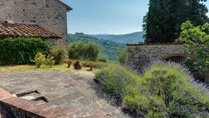 A stone building with a tiled roof, a stone pathway, and lavender bushes. - Spacious Panoramic Apartment with Pool (Pontassieve)