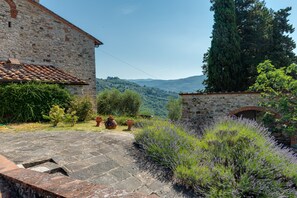 A stone building with a tiled roof, a stone pathway, and lavender bushes. - Spacious Panoramic Apartment with Pool (Pontassieve)