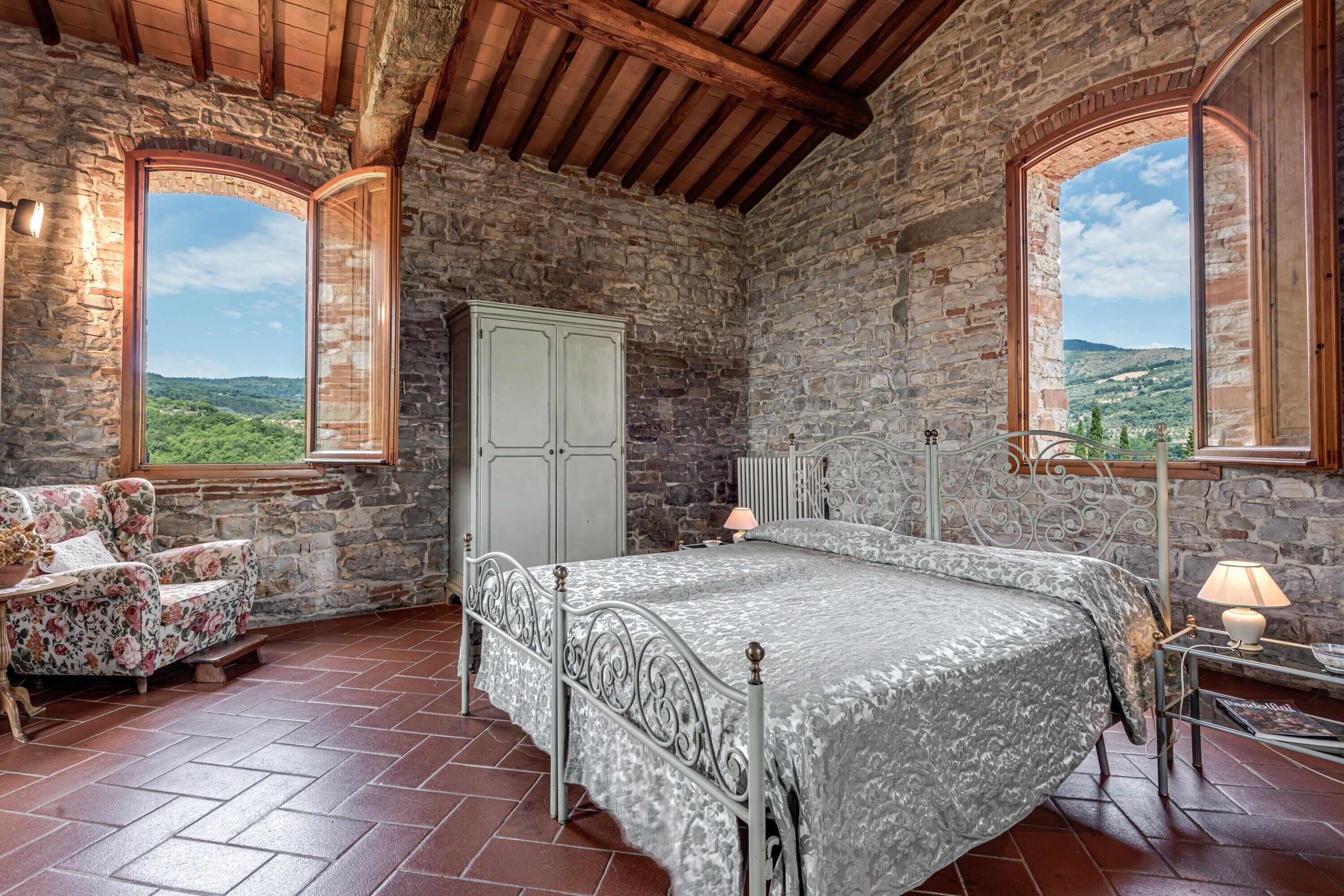 Une chambre rustique aux murs de pierre, avec un lit, une chaise et une armoire.