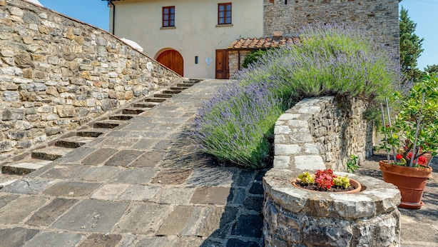 Una scala in pietra che conduce a un edificio con facciata in pietra e una porta in legno.