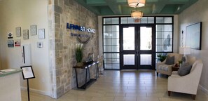 A reception area with a stone wall, a sign for Lennar Homes, a reception desk, and a large glass door leading outside. - New Listing-Modern Storey Lake Pool Villa- Disney. (Kissimmee)