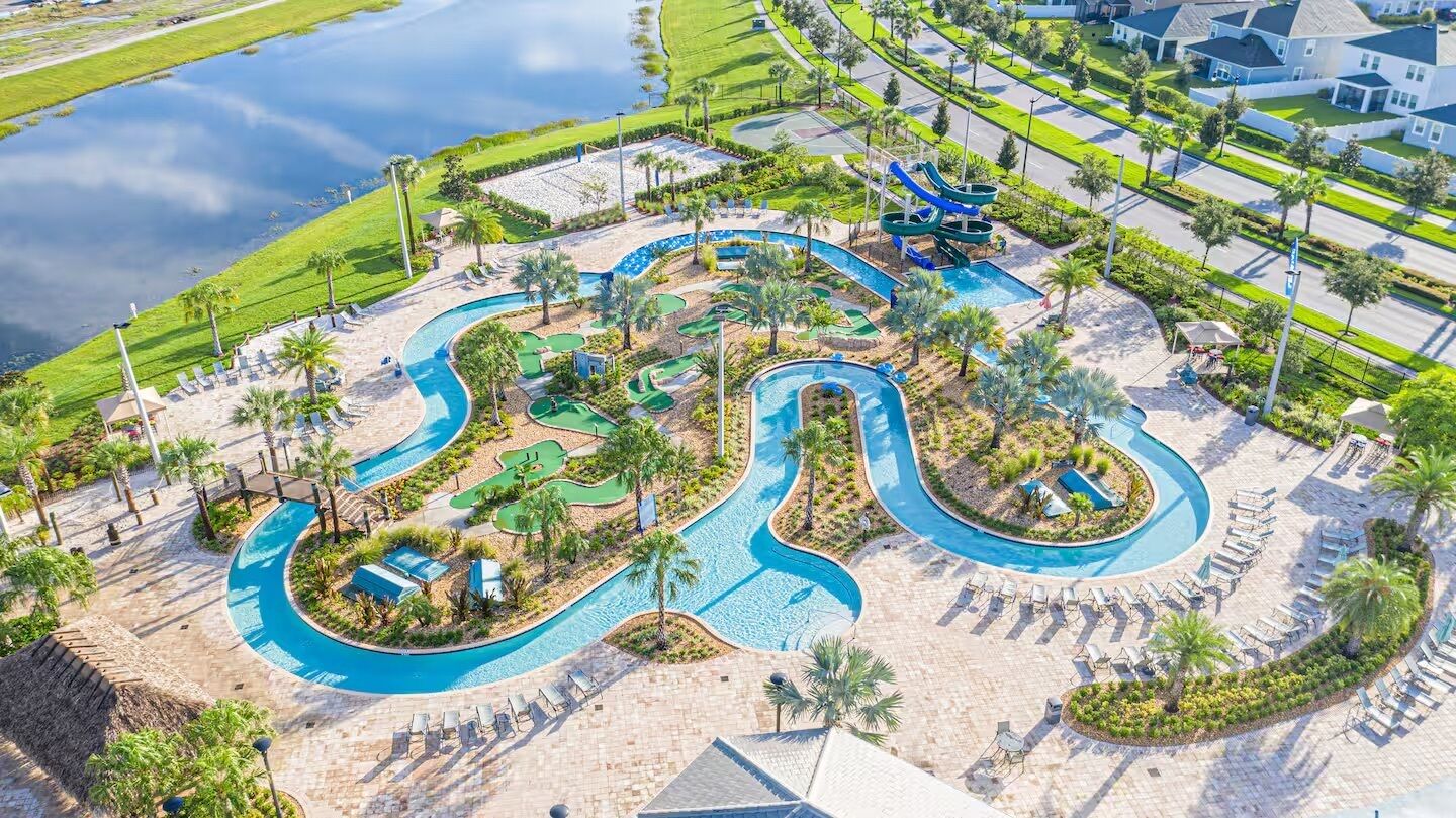 A golf course with a water feature, palm trees, and lounge chairs.