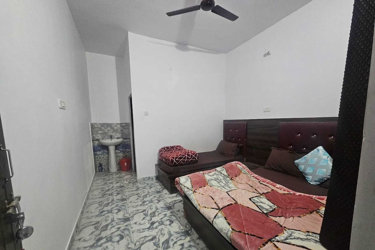 A bedroom with a bed, a ceiling fan, a sink, and a marble-patterned floor.