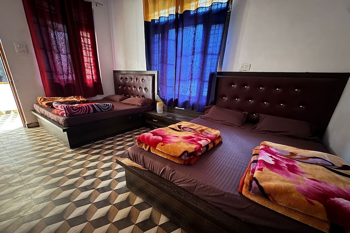 A hotel room with two beds, a patterned floor, and a window with curtains.