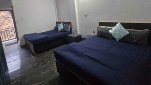 Una habitación con dos camas, un ventilador de techo y una pequeña mesa con botellas de agua.