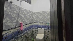 Un baño con inodoro, ducha y un balde en el suelo.