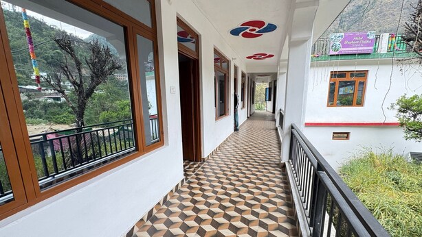 Un pasillo con suelo estampado, ventanas amplias y un balcón con barandilla.