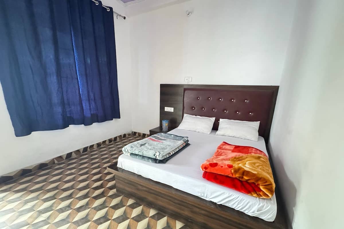 A single bed with a wooden headboard, a patterned floor, and a blue curtain.
