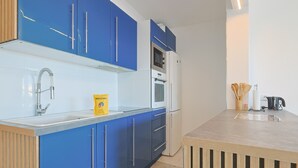 Eine moderne Küche mit blauen Schränken, einer Edelstahl-Spüle und einem eingebauten Ofen.