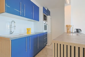 A modern kitchen with blue cabinets, a stainless steel sink, and a built-in oven. - 222 - L Azur in Cannes (Cannes)