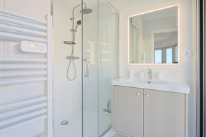 A modern bathroom with a glass shower enclosure, a white sink, and a mirror above the sink. - 222 - L Azur in Cannes (Cannes)