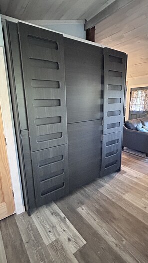 A room with a sliding door, wooden flooring, and a sofa in the background.