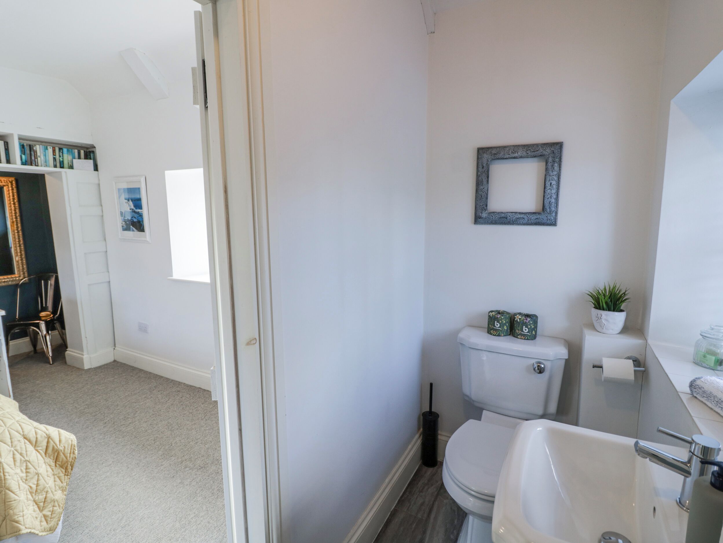 A bathroom with a toilet, sink, and a framed picture on the wall.