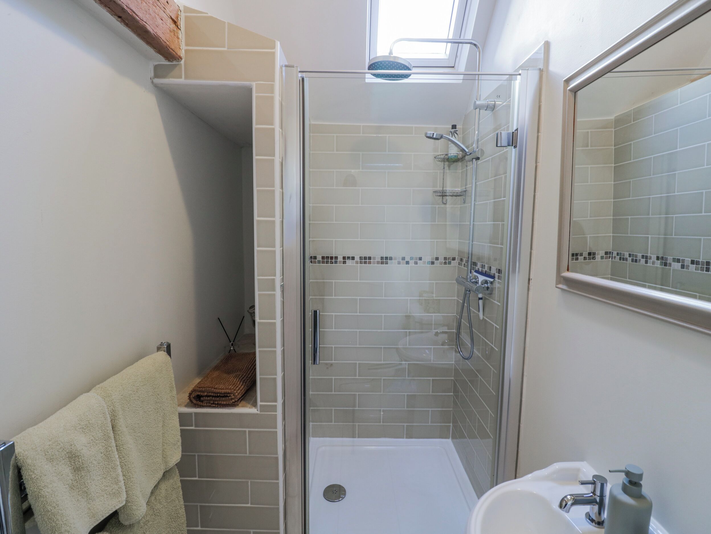 A modern bathroom with a glass-enclosed shower, a white sink, and a mirror.